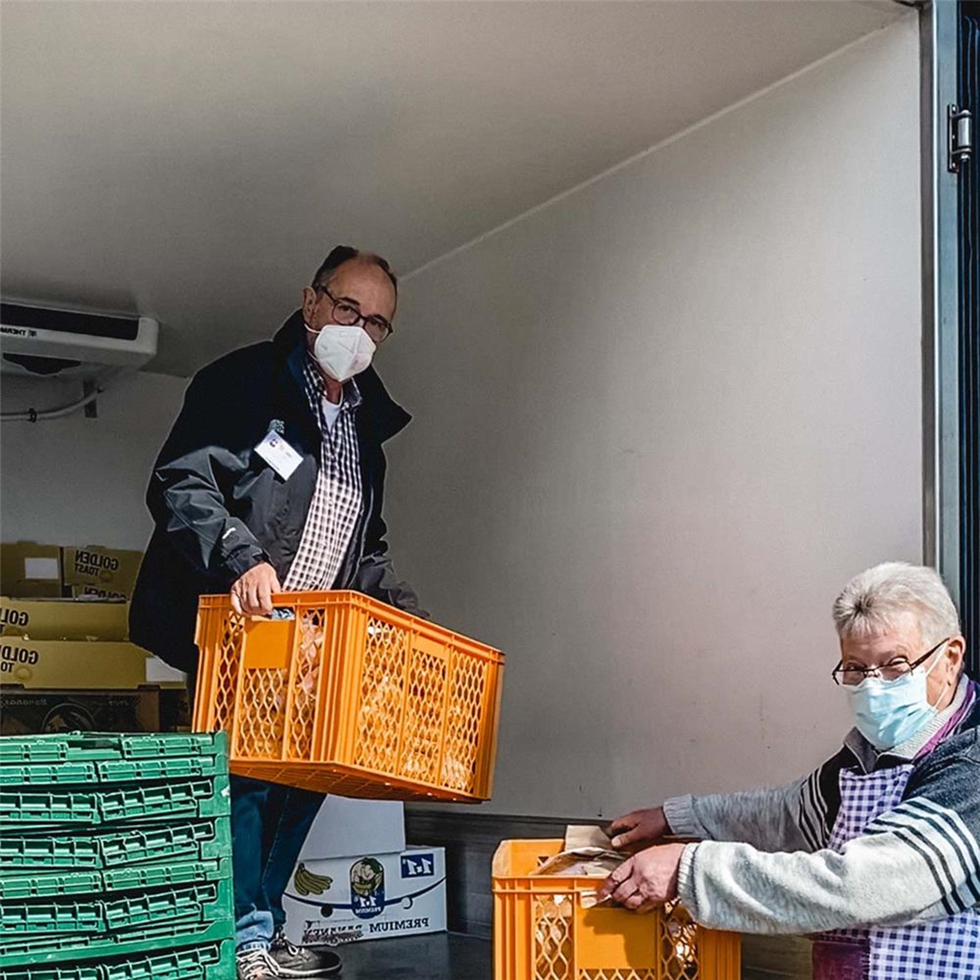 ehrenamtliche Helfer verladen Lebensmittelkisten
